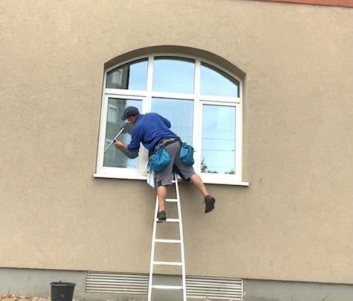 fensterputzer-hangt-von-leiter-mit-abzieher